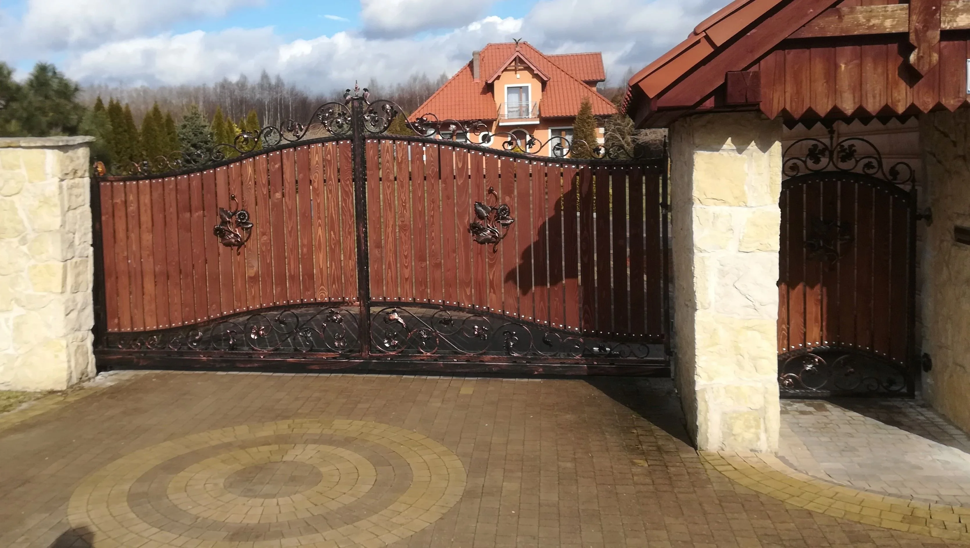 Brama przesuwna kuta z drewnianą deską